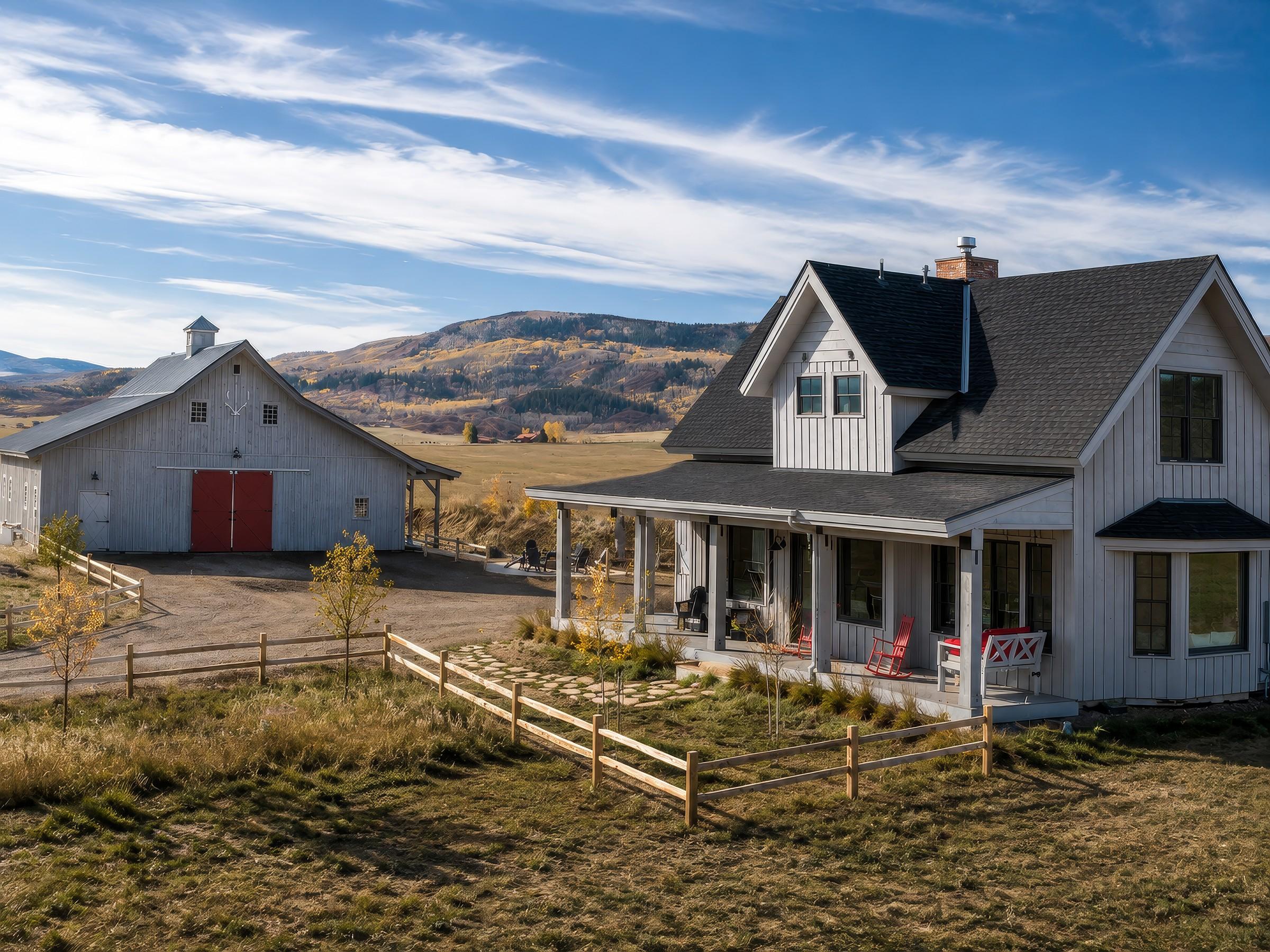Farmhouse and barn exterior with mountain backdrop in daylight