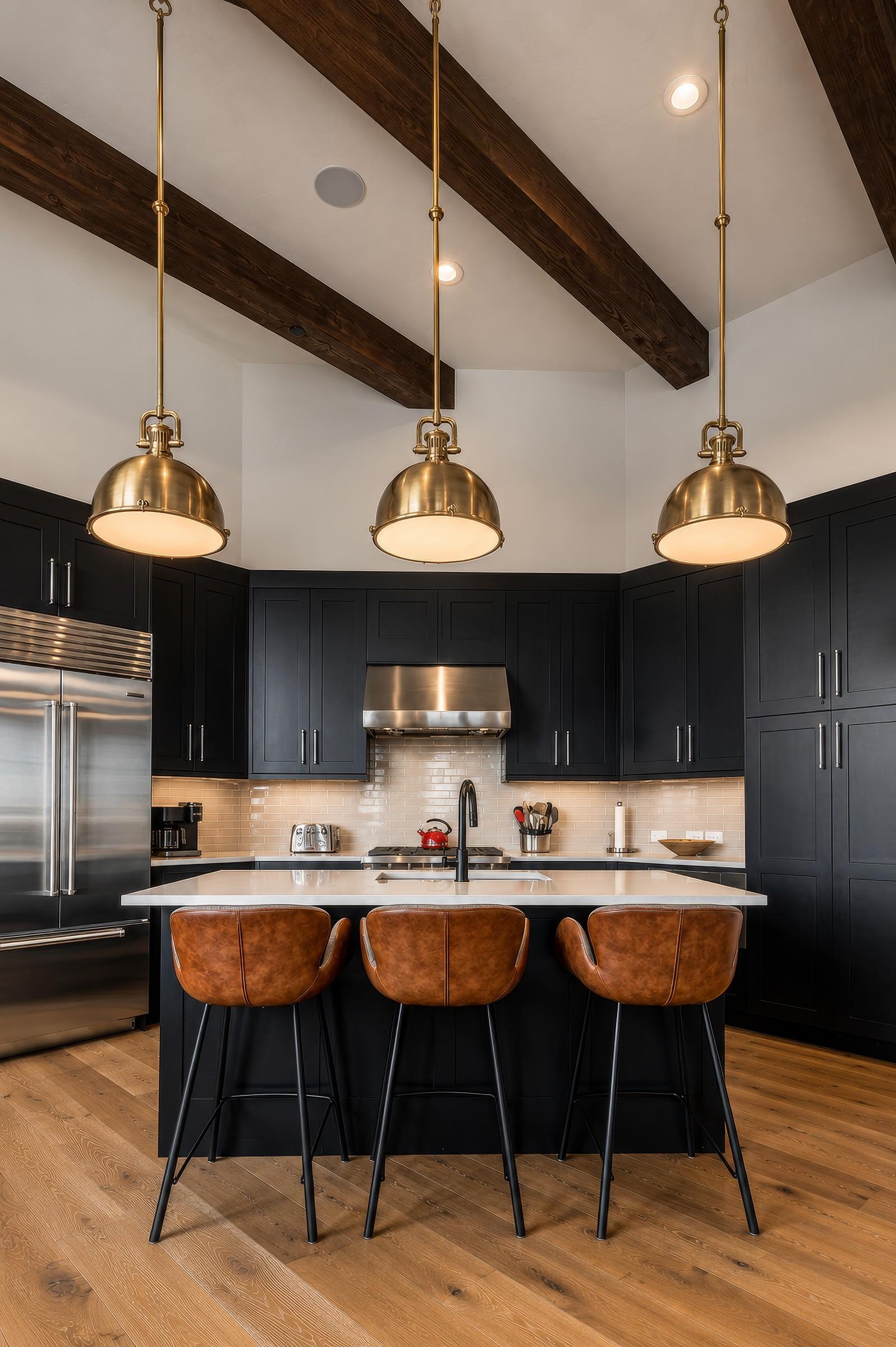 Kitchen island with black cabinetry and brass dome pendants