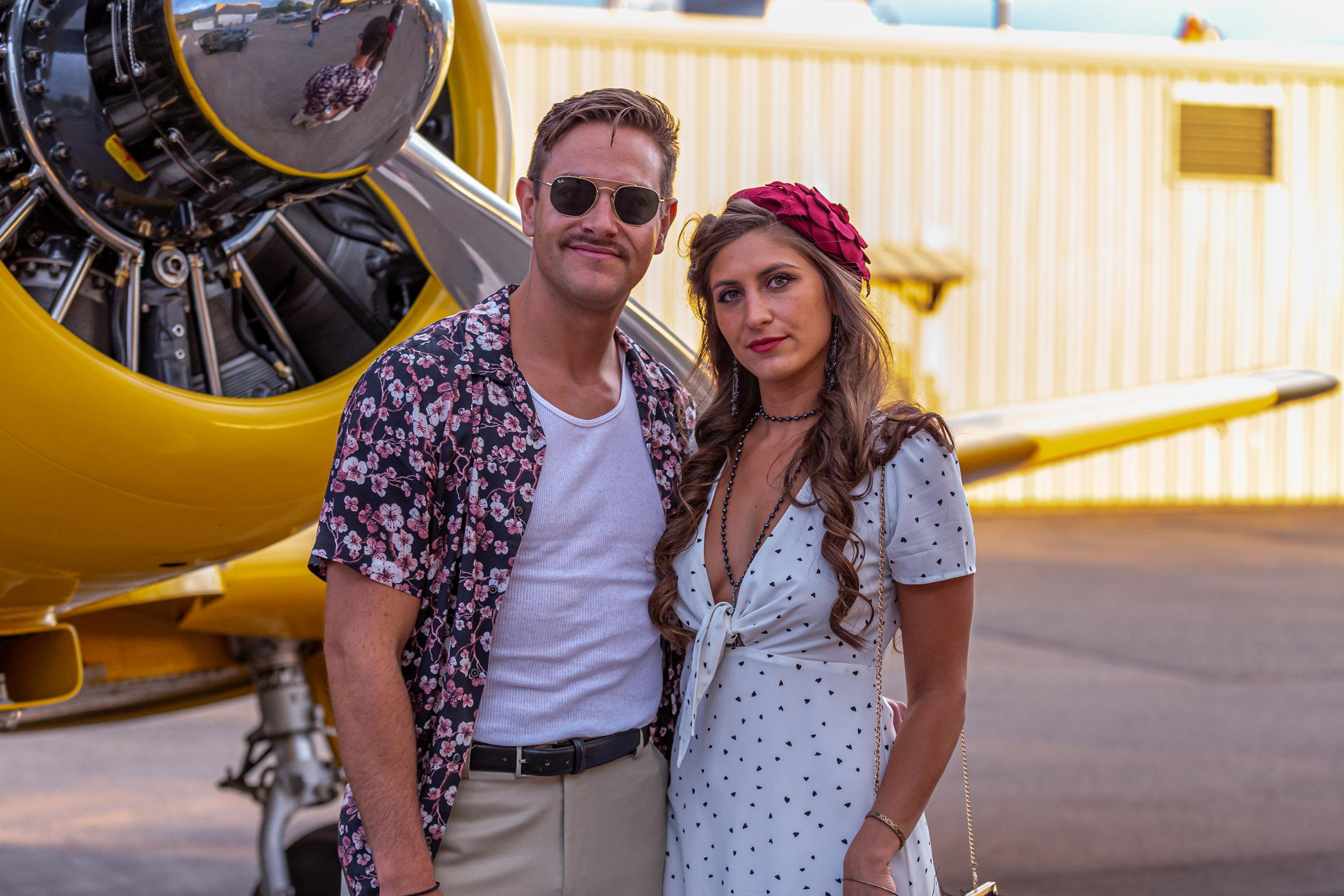 Couple in vintage attire beside a classic aircraft