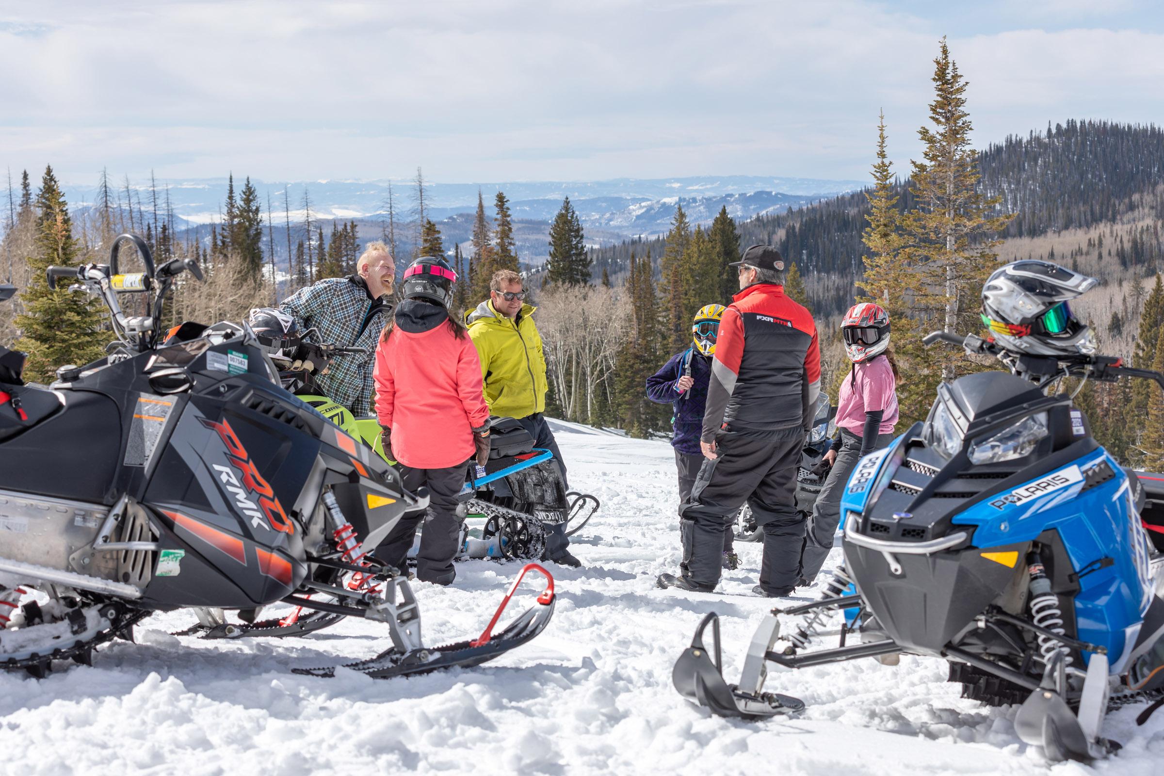 Snowmobile riders gathered on a mountainside