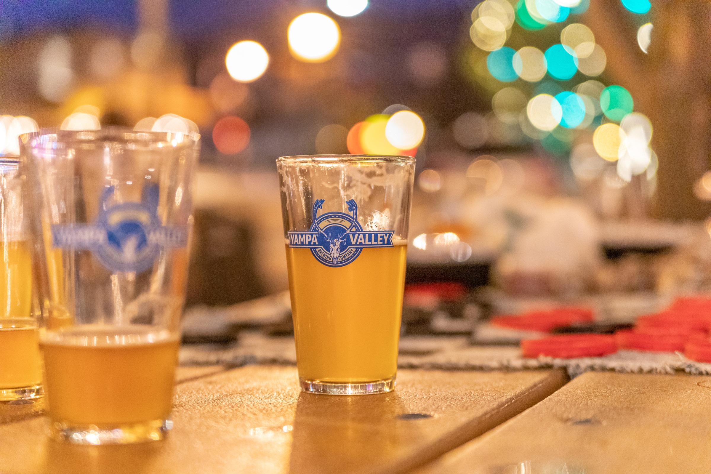 Pint glasses on a taproom table with bokeh lights
